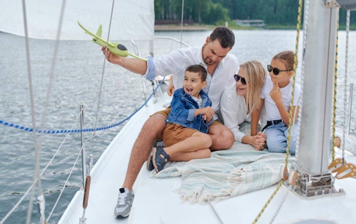 Full body of family in summer clothes having fun together on yacht in summer day